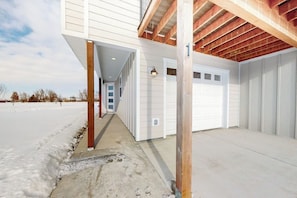 A building with a covered garage and a concrete pathway leading to a door. - Charming home with mountain view, fireplace, balcony, & washer/dryer (Belgrade)