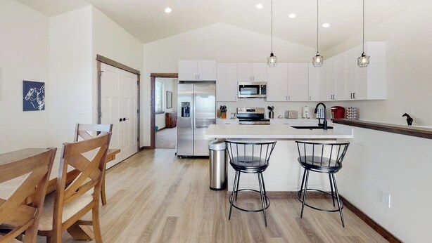 A modern kitchen with white cabinets, stainless steel appliances, and a central island with bar stools. - Charming home with mountain view, fireplace, balcony, & washer/dryer (Belgrade)