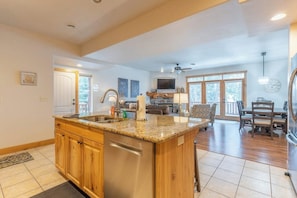 A spacious kitchen with granite countertops, wooden cabinets, and a built-in dishwasher.