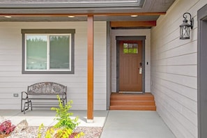 A house with a front porch, a bench, a door, and a window. - Relaxing single-level home with a patio, washer/dryer, & central AC (Lakeside)