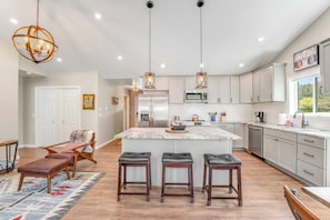 A modern kitchen with a central island, pendant lighting, and a view of the outdoors. - Relaxing single-level home with a patio, washer/dryer, & central AC (Lakeside)