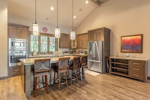 A kitchen with wooden cabinets, stainless steel appliances, and a bar area with stools. - Wilderness retreat with a large deck, grill, updated interior, fireplace, and AC (Lakeside)