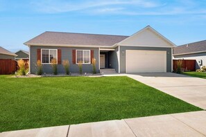 A single-story house with a garage, a well-maintained lawn, and a clear sky. - Bridger View Retreat | House in Belgrade with enclosed backyard, patio, & grill (Belgrade)