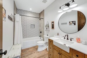 A modern bathroom with a bathtub, toilet, and vanity with a large mirror. - Newly built mountain home with water views, balcony, two kitchens, & W/D (Lakeside)