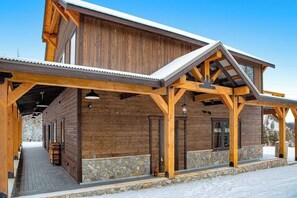 A wooden lodge with a covered porch and stone foundation. - Newly built mountain home with water views, balcony, two kitchens, & W/D (Lakeside)