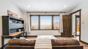 Una habitación con un ventanal grande, un sofá, un escritorio con una silla y un armario.