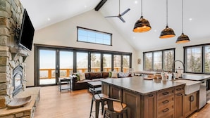 Una cocina amplia con una isla grande, chimenea de piedra y ventanas que ofrecen vistas al exterior.