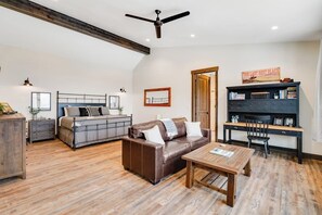 A spacious living area with a ceiling fan, a sofa, a coffee table, and a bookshelf. - Newly built mountain home with water views, balcony, two kitchens, & W/D (Lakeside)