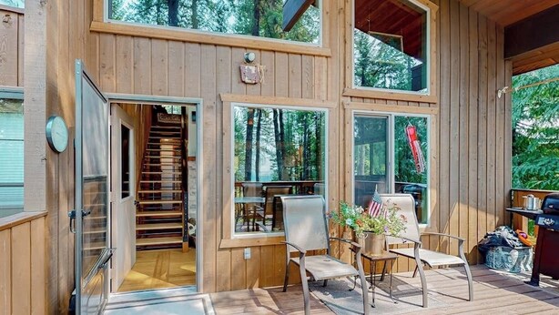 Eine Holzhütte mit einer Terrasse, Sitzgelegenheiten im Freien und einer Treppe zu einer oberen Ebene.