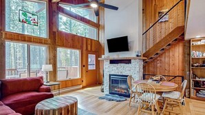 Ein geräumiges Wohnzimmer mit Kamin, Holzböden, einem Fernseher und einer Treppe.