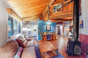 Ein gemütliches Wohnzimmer mit hohen Decken, einem Essbereich und einem Kaminofen.