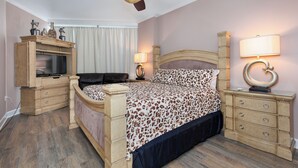 Ein Schlafzimmer mit Bett, Fernseher, Deckenventilator, Nachttisch, Lampe und Kommode.