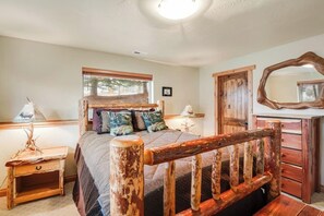 A bedroom with a wooden bed frame, a nightstand, a dresser, and a mirror. - Spacious 2-story home with deck, fireplace, & W/D - near Glacier National Park (Whitefish)