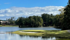En golfbane med en sø, træer og en bygning i baggrunden.