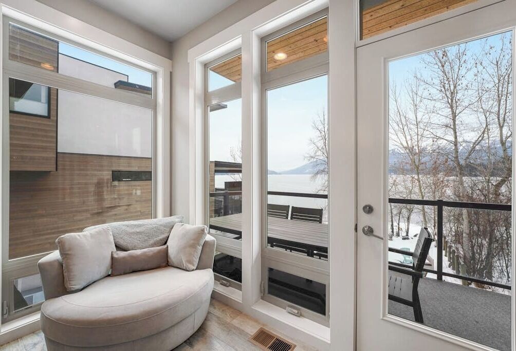 A modern interior with a curved sofa, large windows, and a view of a snowy landscape.