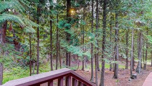 A forested area with a wooden deck. - Charming condo with lake access, shared pools and hot tub, WiFi, and fireplace (Whitefish)