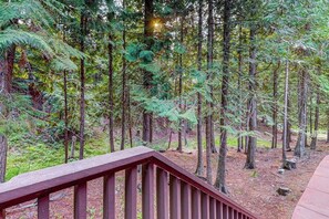 A forested area with a wooden deck. - Charming condo with lake access, shared pools and hot tub, WiFi, and fireplace (Whitefish)