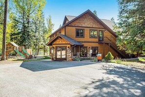 A lodge with a large wooden structure, a covered entrance, and a staircase leading to the upper level. - Cozy condo with deck, wood stove, pool, sauna, tennis - near skiing & fishing (Whitefish)