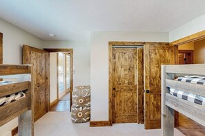 A bedroom with a bunk bed, wooden doors, and a patterned ottoman. - Big Horn ski-in/ski-out townhome with private indoor hot tub, by Lake Levinsky (Big Sky)