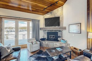 Ein Wohnzimmer mit Kamin aus Stein, einem darüber montierten Fernseher und einem Sofa.