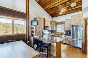 Eine moderne Küche mit Holzausstattung, Edelstahlgeräten und einer großen Kochinsel mit Barhocker.
