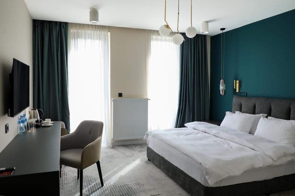 Ein Hotelzimmer mit Bett, Schreibtisch, Stuhl, Fernseher und Heizkörper.