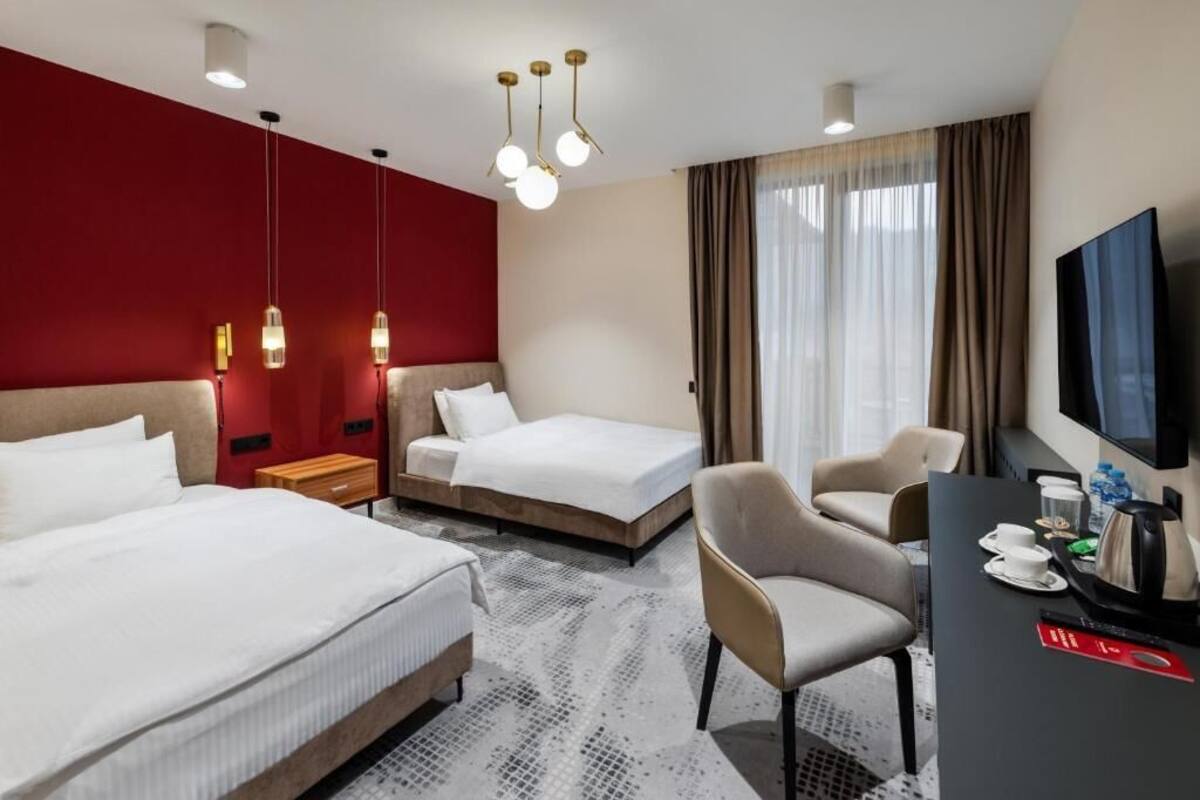 A hotel room with two beds, a desk with a TV, and a chair.