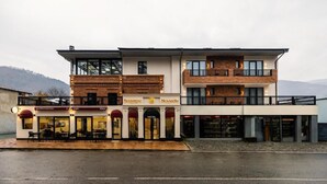 Un hotel de tres pisos con restaurante en la planta baja, restaurante en el segundo piso y balcón en el tercero.