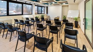 Un salón de conferencias con filas de sillas, una pizarra y un proyector.