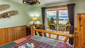 Ein Zimmer mit einem Bett, einem Tisch, einer Lampe und Blick ins Freie.