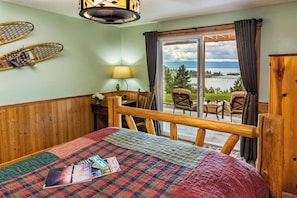 Ein Zimmer mit einem Bett, einem Tisch, einer Lampe und Blick ins Freie.