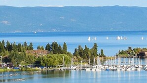 Ein Yachthafen mit Booten, ein ruhiger See und ein bewaldeter Hügel im Hintergrund.