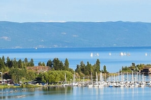 Ein Yachthafen mit Booten, ein ruhiger See und ein bewaldeter Hügel im Hintergrund.