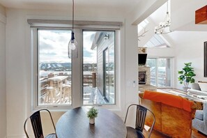 Ein Essbereich mit Tisch, Stühlen und Blick durch ein großes Fenster.