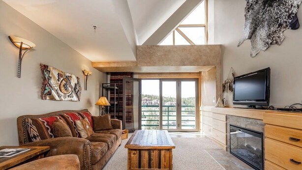 Amplia sala de estar con un ventanal grande, chimenea y televisor.