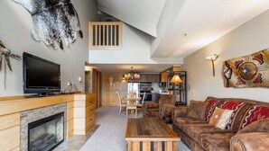 Amplia sala de estar con chimenea, sofá de cuero y televisión.