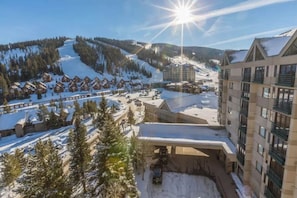 Ein Skigebiet mit Chalet-ähnlichen Gebäuden, einem Parkplatz und einem größeren Gebäude mit Balkonen.