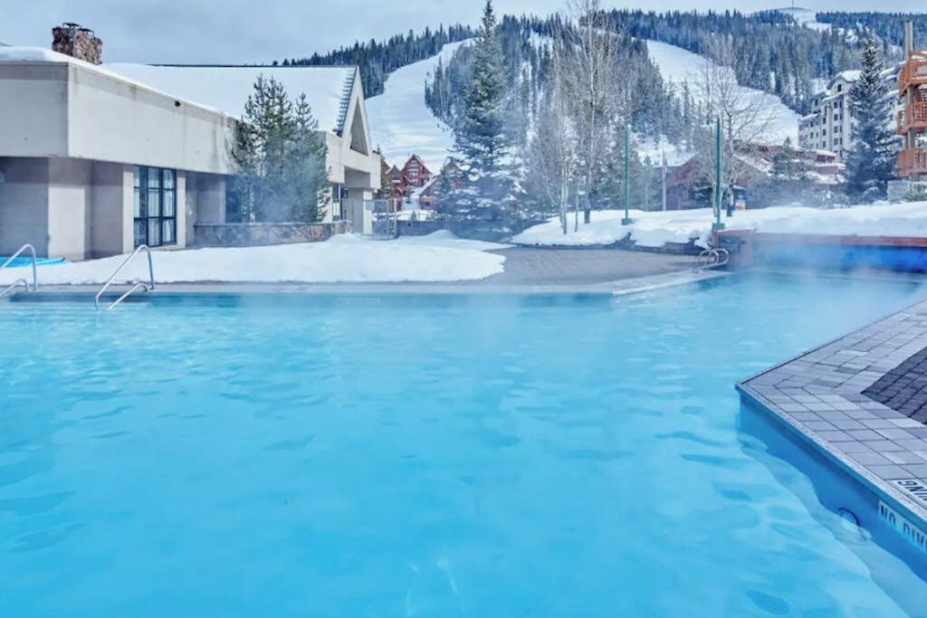 Une piscine avec vue sur une station de ski et des bâtiments en arrière-plan.
