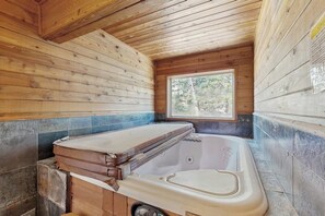 A wooden cabin interior with a hot tub, a window, and a tiled floor. - Slopeside ski-in/ski-out condo with private hot tub & panoramic views (Big Sky)