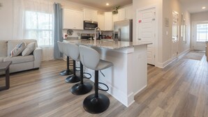 Eine moderne Küche mit weißen Schränken, einem Edelstahlkühlschrank und einer Bar mit Sitzgelegenheiten.