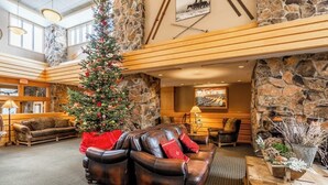 Een hal met een stenen muur, leren banken, een kerstboom en een open haard.
