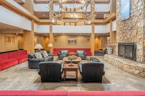 A spacious lobby with a stone fireplace, leather seating, and a chandelier. - Condo with hot tub & pool - prime ski-in/out location (Big Sky)