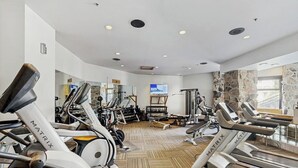 Une salle de sport équipée de tapis de course, de vélos elliptiques et de matériel de musculation.