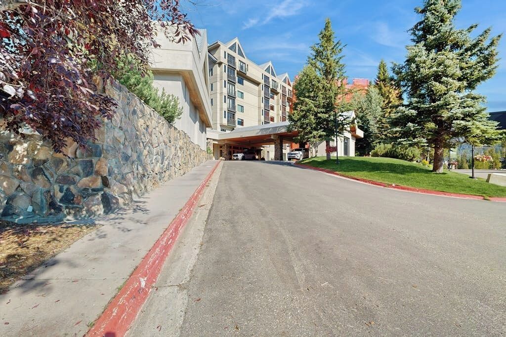 A multi-story hotel with a stone facade, a covered entrance, and a parking area.