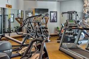 Ein Fitnessstudio mit Laufbändern, Kraftgeräten und einer Spiegelwand.