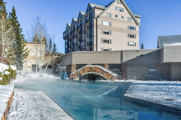 Ein modernes Hotel mit Pool, einem steinernen Bogen und einem mehrstöckigen Gebäude mit Balkonen.