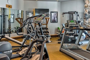 Ein Fitnessraum mit Laufbändern, Kurzhanteln und Trainingsgeräten.