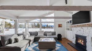 A modern living room with a sectional sofa, a fireplace, and large windows. - Beautiful, modern townhome next to the golf course with WiFi and full kitchen (Jackson)