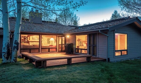 A modern house with a deck, large windows, and a visible garage.