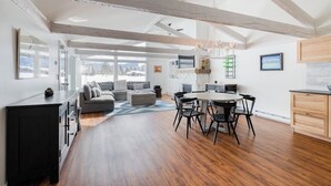 A spacious living area with a dining table and chairs, a sofa, and a kitchen area with a countertop and cabinets. - Beautiful, modern townhome next to the golf course with WiFi and full kitchen (Jackson)